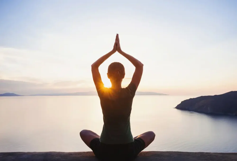 A lady doing a yoga while sunset/sunrise as a sample for Yoga Yacht Charter