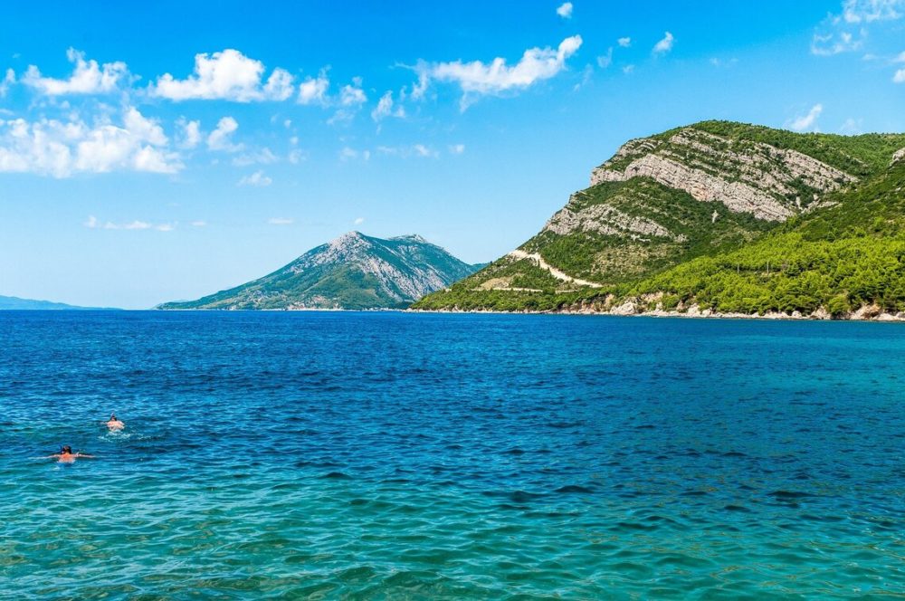 Peljesac Peninsula. Blue and aqua water with green mountains in the background.
