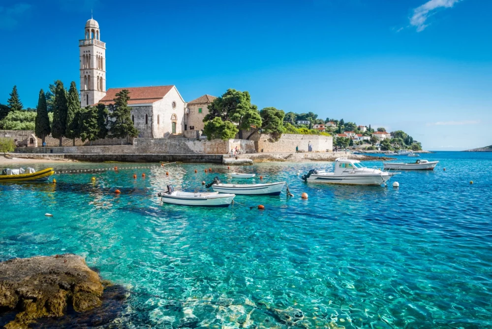 Beautiful aqua water with boats with church in background, Hvar, Croatia