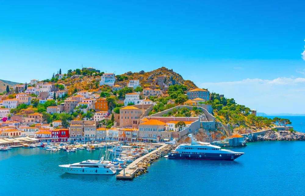 Colorful hillside houses in the background of Hydra Island port with boats and dock in foreground.