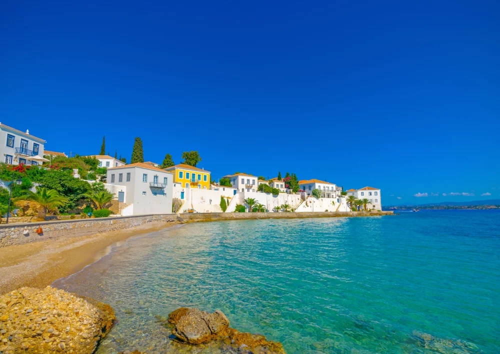 Calm aqua water in front of colorful buildings on Spetses Island Greece.