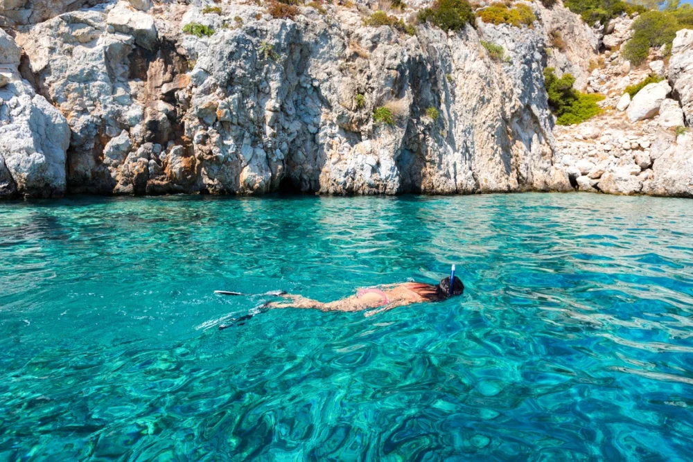 Woman snorkeling in the clear aqua water on Agistri Island Greece. 