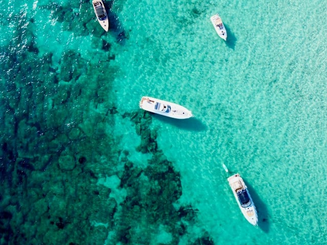 four small boats in shallow ocean waters