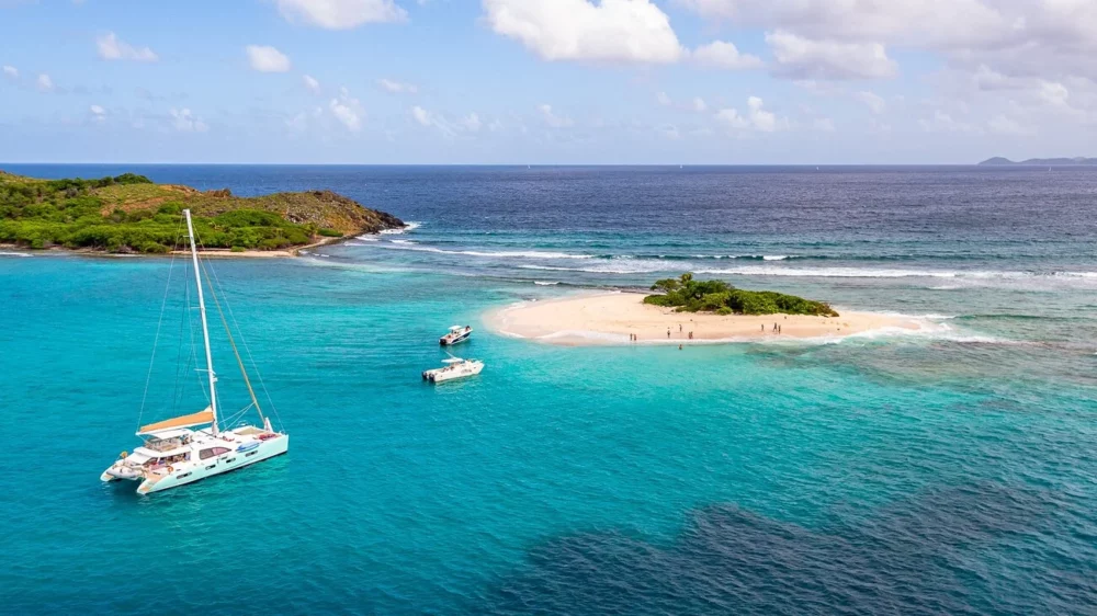 Aerial view of a catamaran yacht anchored at Ssandy Spit Island in the turquoise waters of the British Virgin Islands, ideal for those looking to charter a yacht in the Caribbean.