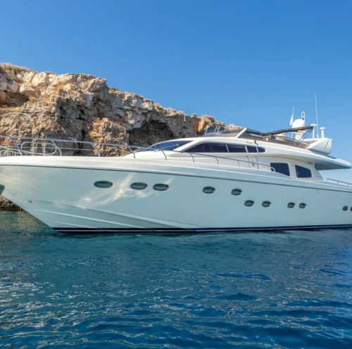 The AMORAKI motor yacht anchored near rocky cliffs, showcasing its sleek design and luxurious features, perfect for a rent-a-yacht adventure.