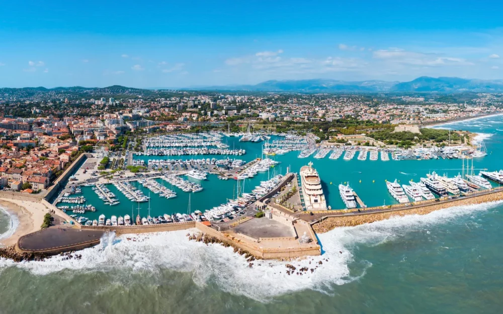 Aerial view of Antibes, France, featuring a bustling marina filled with yachts and sailboats, highlighting the appeal of private crewed yacht charters.