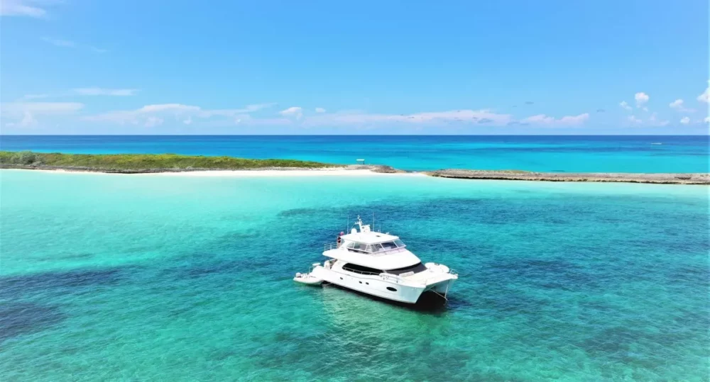 A luxurious crewed yacht charter anchored in the crystal-clear waters of the British Virgin Islands, surrounded by vibrant blue sea and a picturesque coastline.






