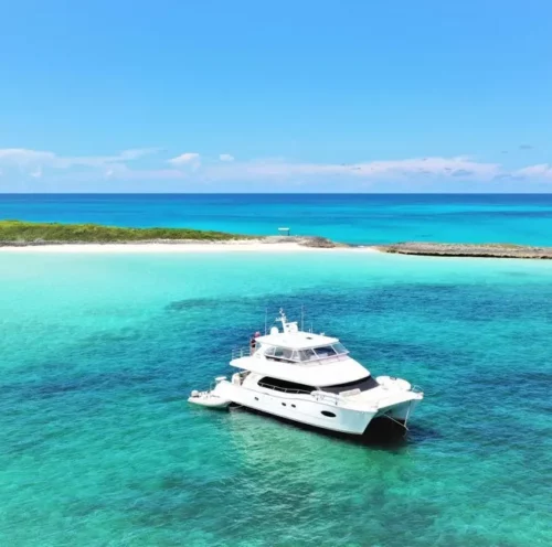 A luxurious crewed yacht charter anchored in the crystal-clear waters of the British Virgin Islands, surrounded by vibrant blue sea and a picturesque coastline.