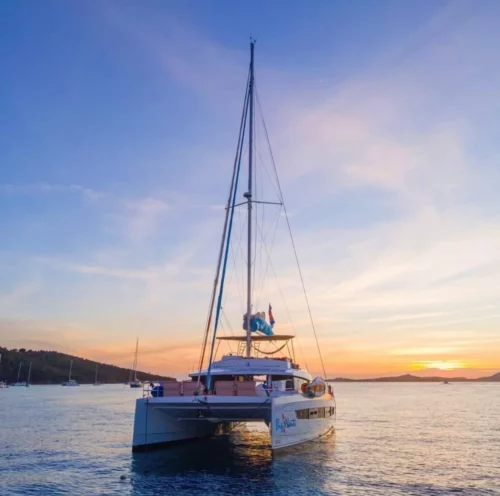 Sailing Catamaran BIG NAUTI anchored in the tranquil waters of the US Virgin Islands during a picturesque sunset, showcasing an idyllic yacht trip.