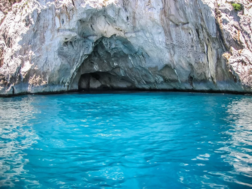 Entrance to the Blue Grotto in Capri, Italy, showcasing vibrant blue waters and impressive rock formations, perfect for an enchanting yacht trip.