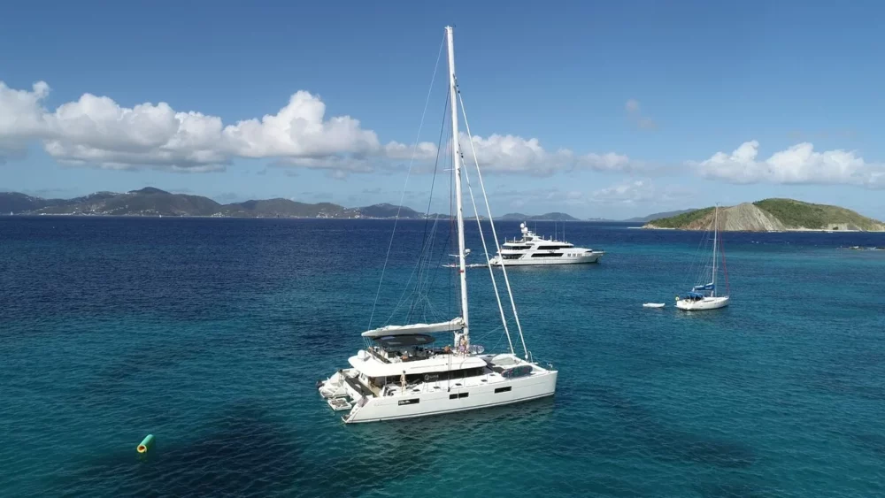 The Eclipse catamaran is anchored in clear turquoise waters with a small island in the background. The boat is perfect for families and groups of friends looking for an affordable yacht charter experience.