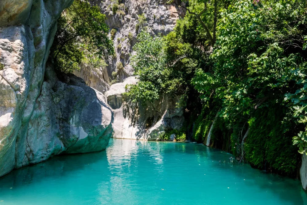 Dramatic rock formations rise above the emerald waters of Göynük Canyon National Park, Turkey. Experience a different side of Turkey on a private sailboat charter.
