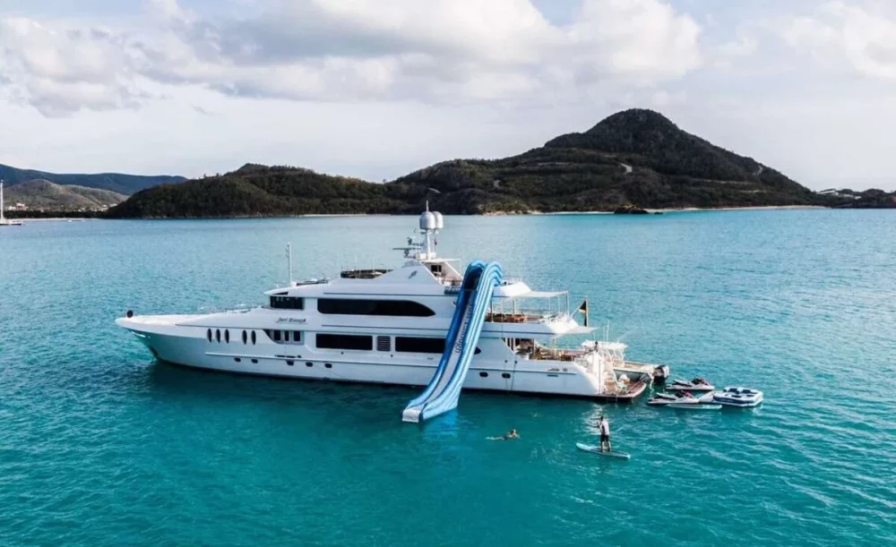Anchored in the clear blue waters of the British Virgin Islands. The yacht has a water slide attached to its side, a perfect relaxation for a private yacht charters Caribbean.