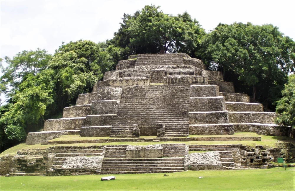 Ancient Mayan Ruins in Belize surrounded by lush greenery, showcasing a stepped pyramid structure.