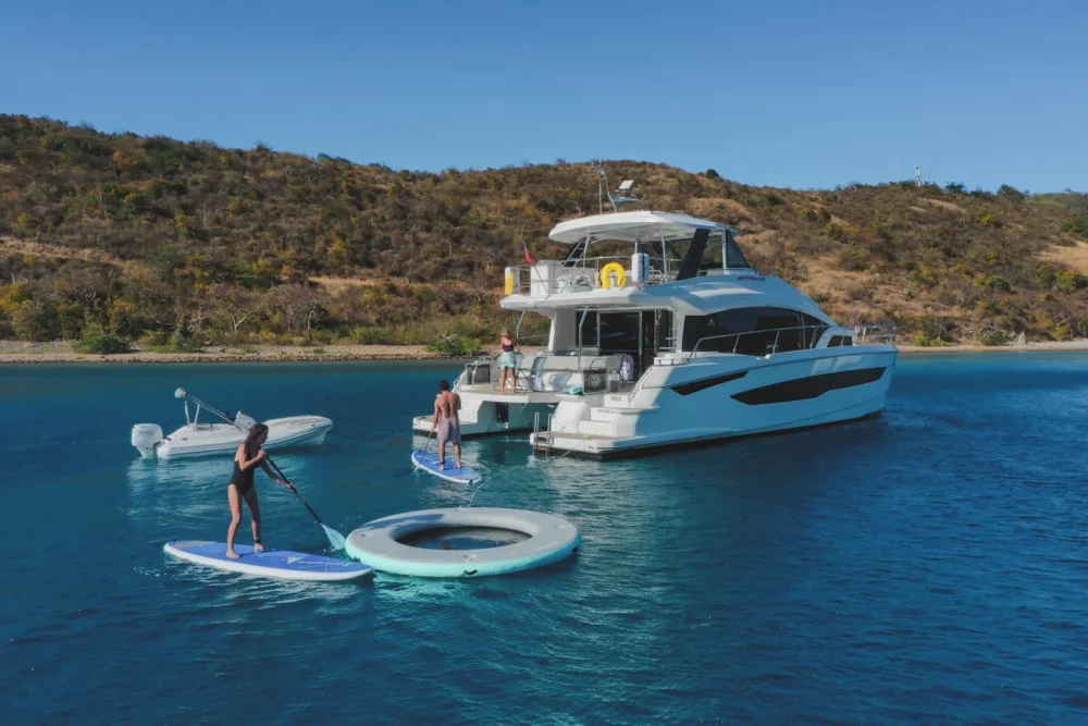 Guests enjoying water activities near a luxury yacht during a private yacht rental, showcasing the perfect blend of relaxation and adventure.