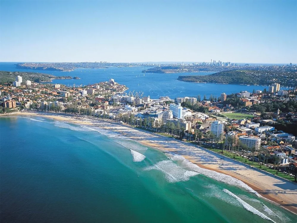 An aerial view of Manly Beach, Sydney, Australia with turquoise water and white sand.