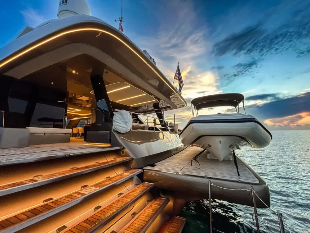 Close-up of the luxurious aft deck of the Nauti Nickel power catamaran, featuring warmly lit teak steps and a tender secured on a platform